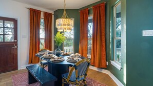 A dining room with a round table set for four, surrounded by chairs, a vase with greenery, and a hanging light fixture. - Austin Compound Pickleball Pool Sauna (Austin)
