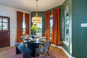 A dining room with a round table set for four, surrounded by chairs, a vase with greenery, and a hanging light fixture. - Austin Compound Pickleball Pool Sauna (Austin)