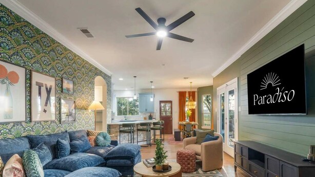 A spacious living room with a sofa set, a coffee table, and a television mounted on the wall. - Austin Compound Pickleball Pool Sauna (Austin)