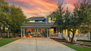 A house with a garage door featuring a mural of Austin, Texas. - Austin Compound Pickleball Pool Sauna (Austin)