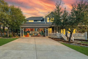 A house with a garage door featuring a mural of Austin, Texas. - Austin Compound Pickleball Pool Sauna (Austin)