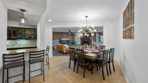 A dining area with a wooden table and chairs, a kitchen in the background, and a living room with a fireplace. - Mountain View - Rooftop Patio - Theater - Games (Gatlinburg)