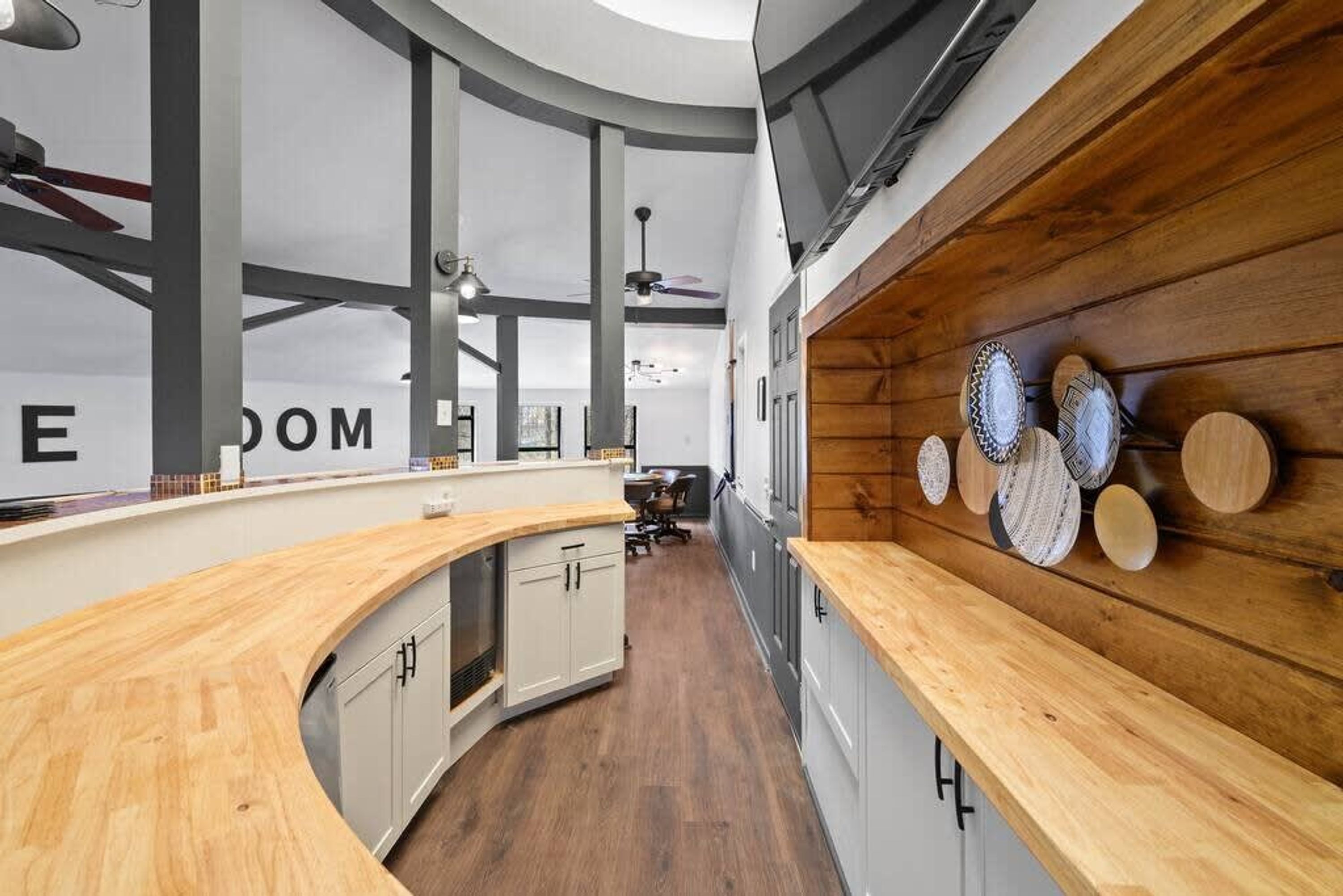 A modern kitchen with wooden countertops, a curved design, and a wall-mounted plate display.