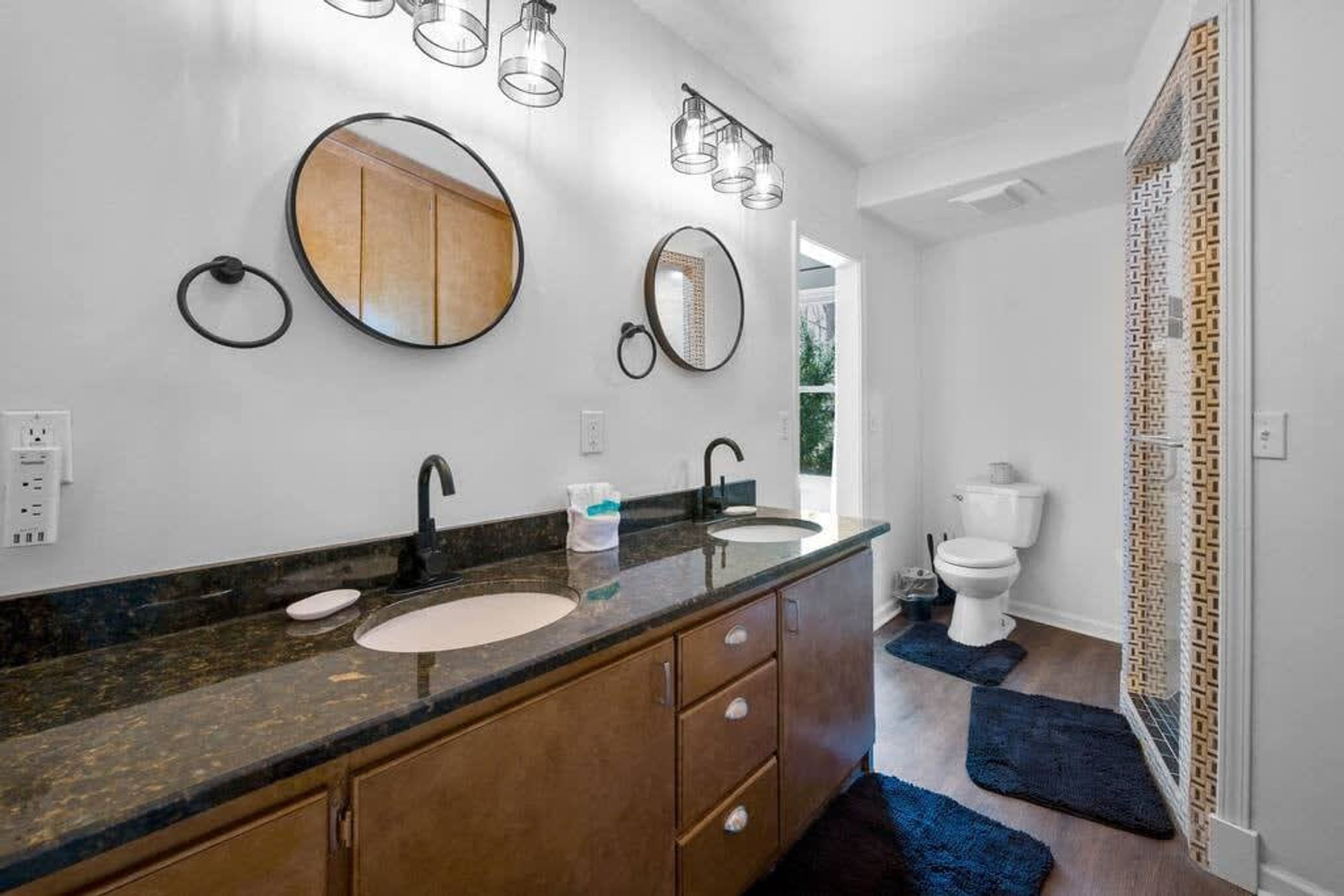 A bathroom with a vanity, sink, and toilet. There are wall-mounted mirrors and a ceiling light fixture.