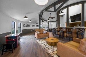 Ein geräumiger Spielraum mit Barbereich, Ledersofas und einem großen Fernsehbildschirm.
