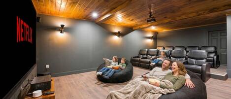 A home theater room with a Netflix logo, a wooden ceiling, and black leather seating.
