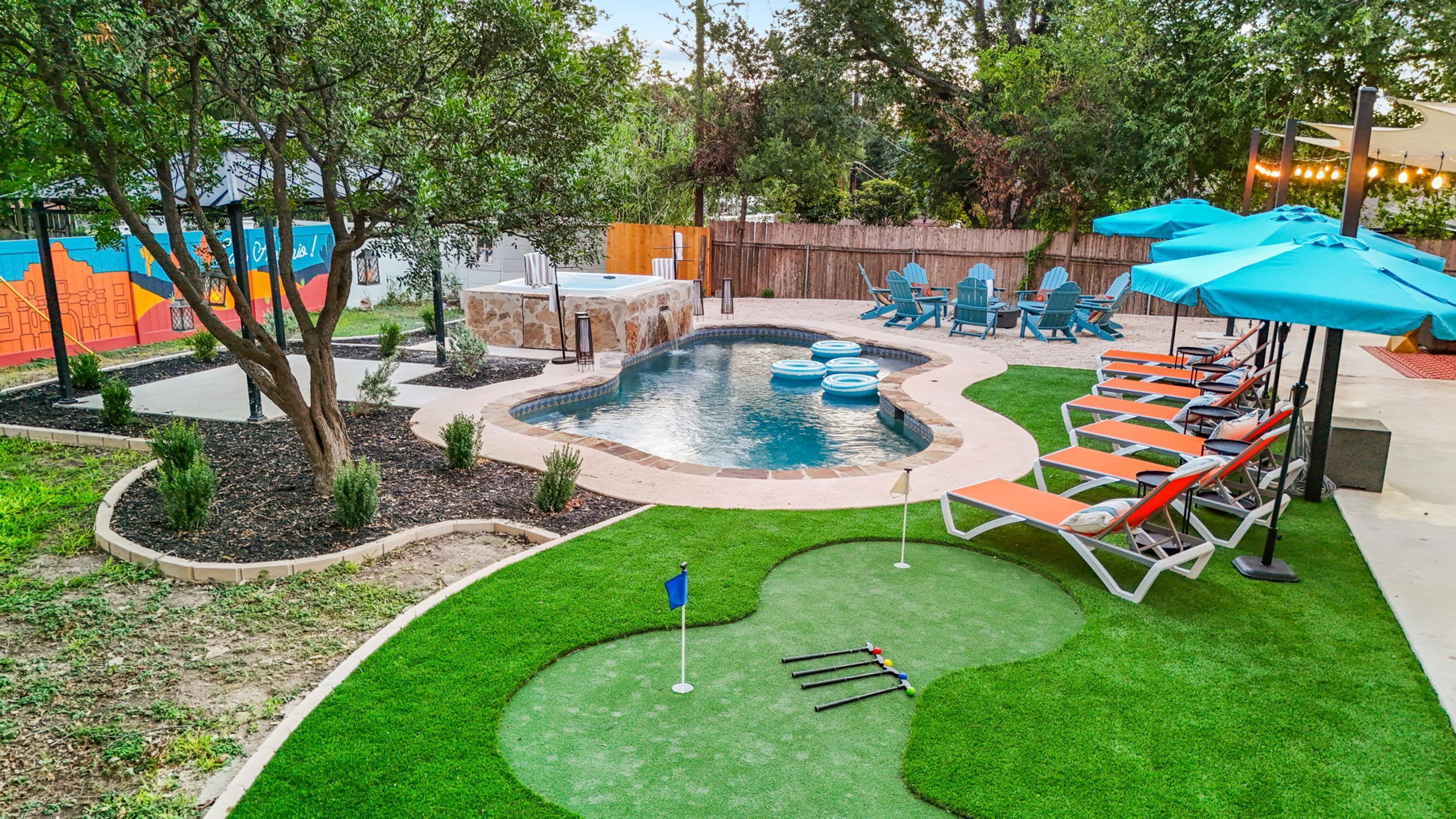 Ein Garten mit Schwimmbad, Liegestühlen und einem Putting Green.