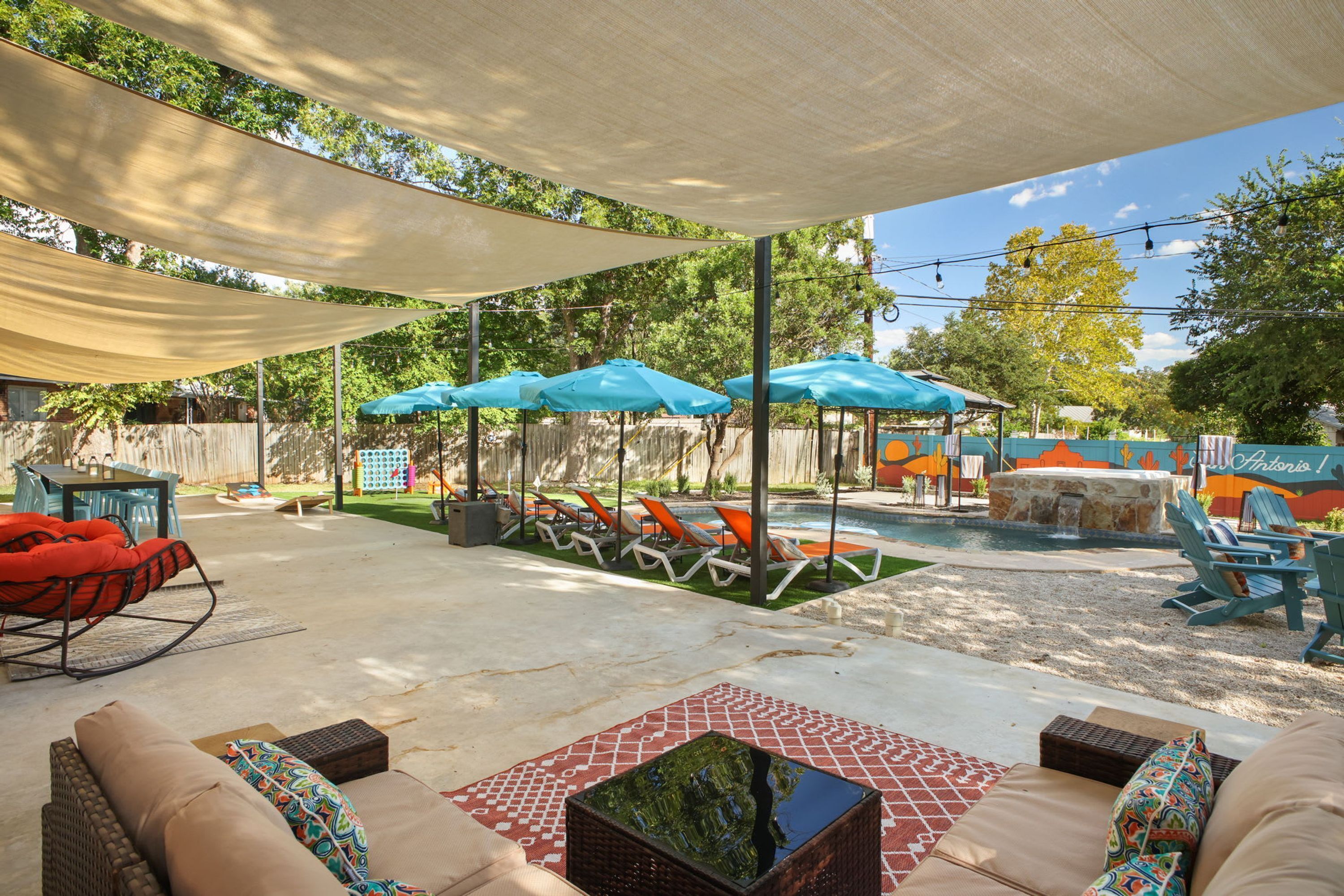 Uma área de estar ao ar livre com espreguiçadeiras, guarda-sóis e piscina.