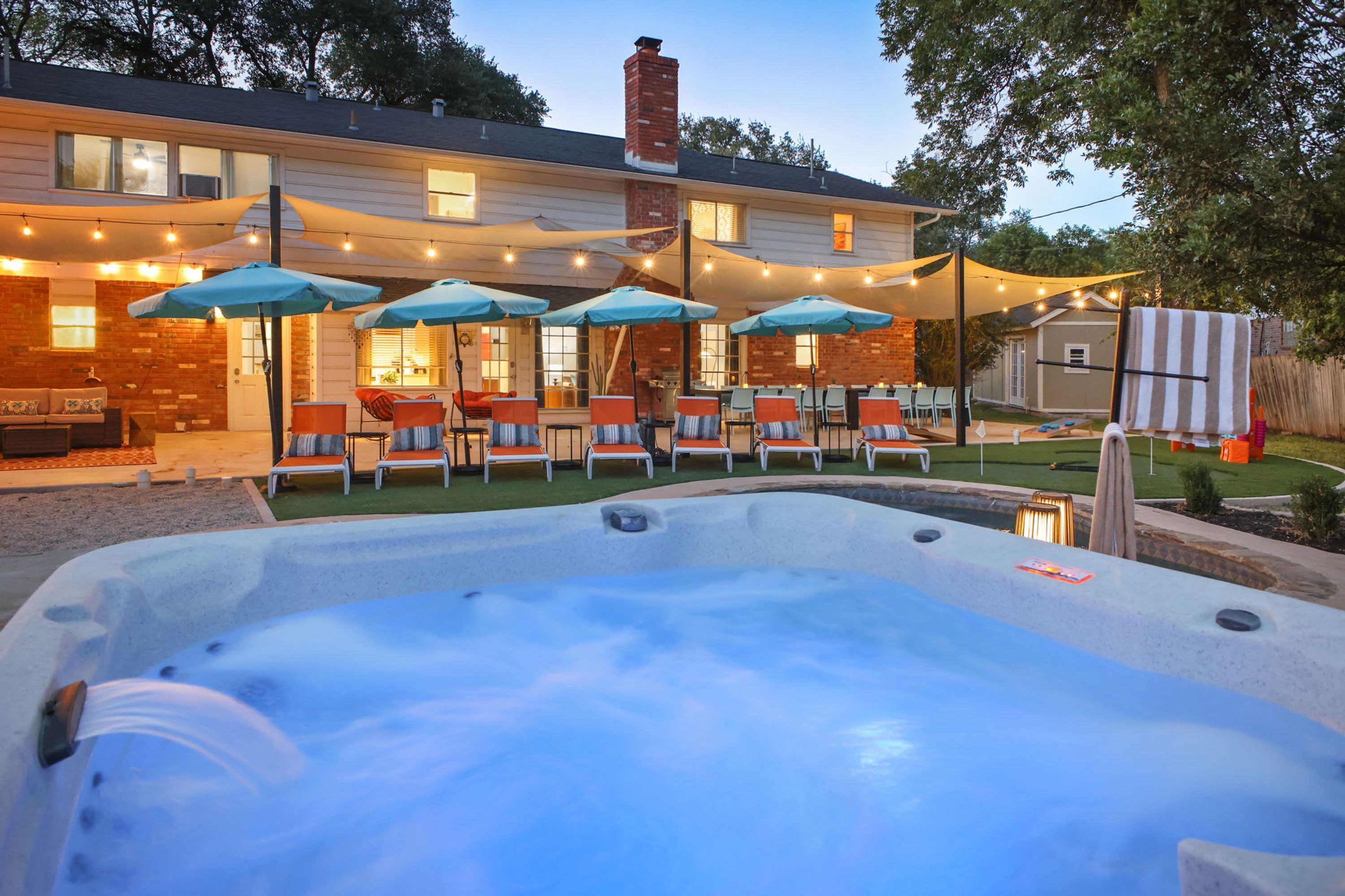 Ein Garten mit Whirlpool, Sitzgelegenheiten im Freien und Lichterketten.