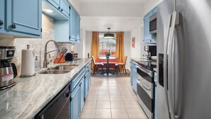 Una cucina moderna con mobili azzurri, elettrodomestici in acciaio inossidabile e un'area pranzo con tavolo e sedie.