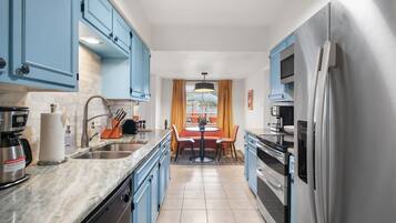 Eine moderne Küche mit blauen Schränken, Edelstahlgeräten und einem Essbereich mit Tisch und Stühlen.