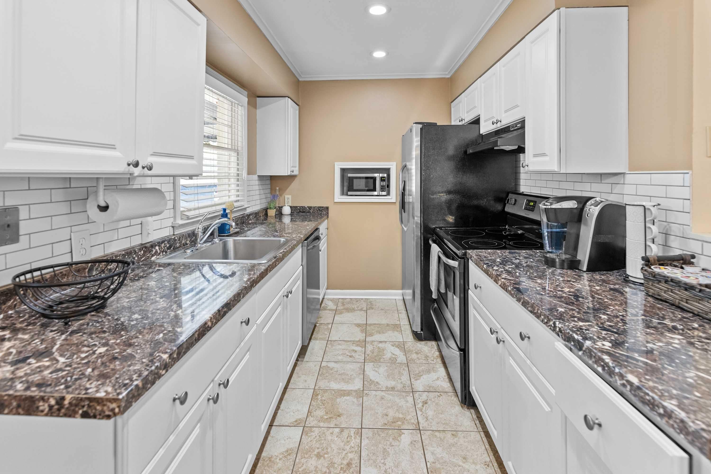 A kitchen with white cabinets, a stainless steel refrigerator, a microwave, and a stove.