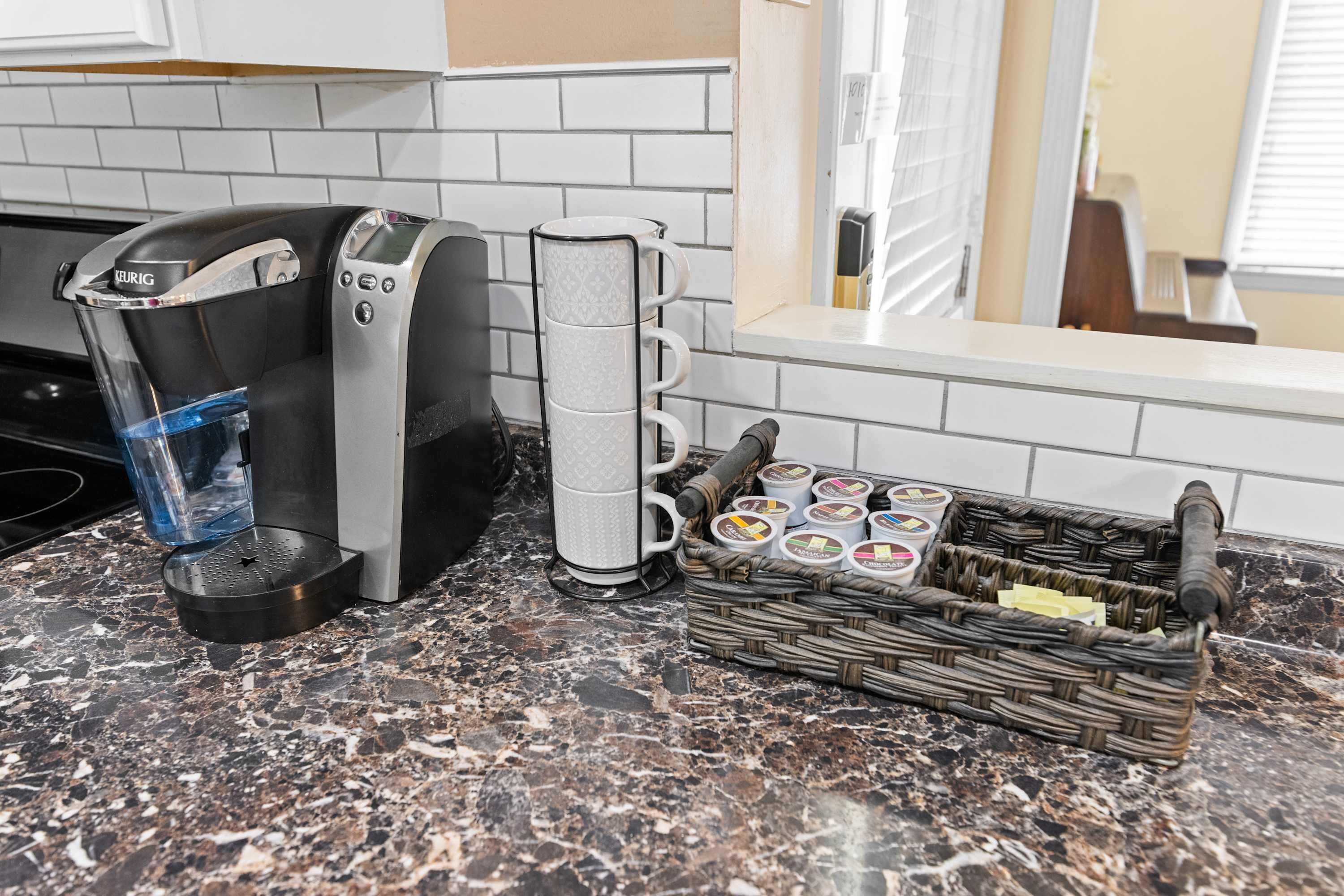 A coffee maker, a mug holder, and a basket of coffee pods on a kitchen counter.