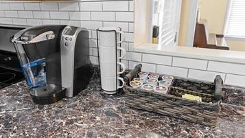 A coffee maker, a mug holder, and a basket of coffee pods on a kitchen counter.