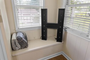 A window seat with a black letter H decoration, a wire basket with a gray blanket, and a white wall. - Modern Memphis Retreat - Sleeps 7 - Fireplace (Memphis)