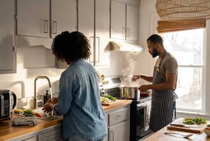A modern kitchen with stainless steel appliances, a wooden countertop, and a window providing natural light. - Coastal 1BR Retreat Spa Walk to Dining Water (Warren)