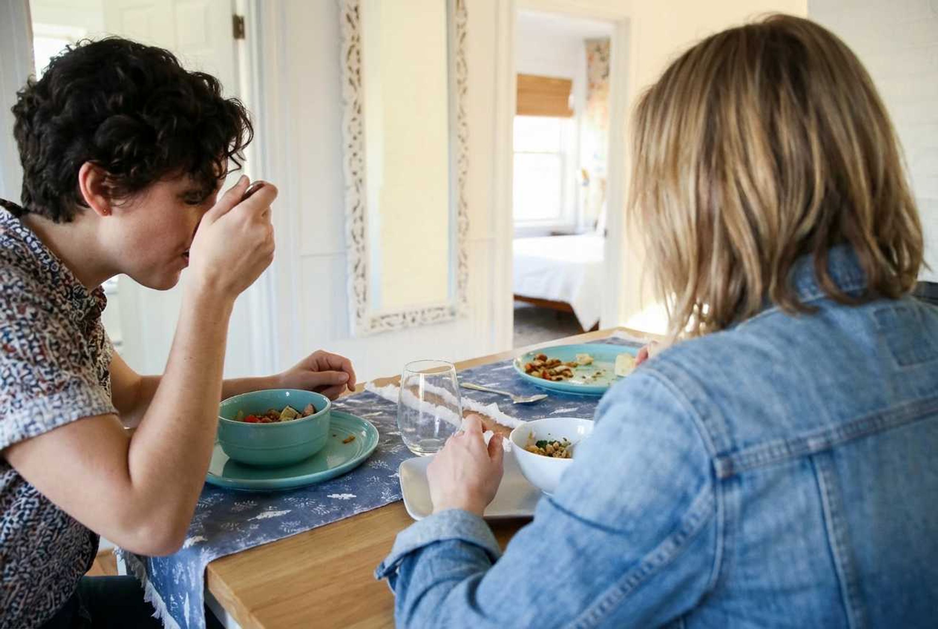 Een eettafel met twee personen, een kom en een glas.