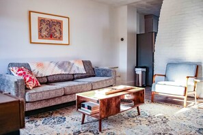 A living room with a grey sofa, a coffee table, a chair, and a framed artwork on the wall. - Coastal 1BR Retreat Spa Walk to Dining Water (Warren)