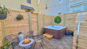 Une terrasse en bois avec un jacuzzi, un foyer extérieur et du mobilier de jardin.