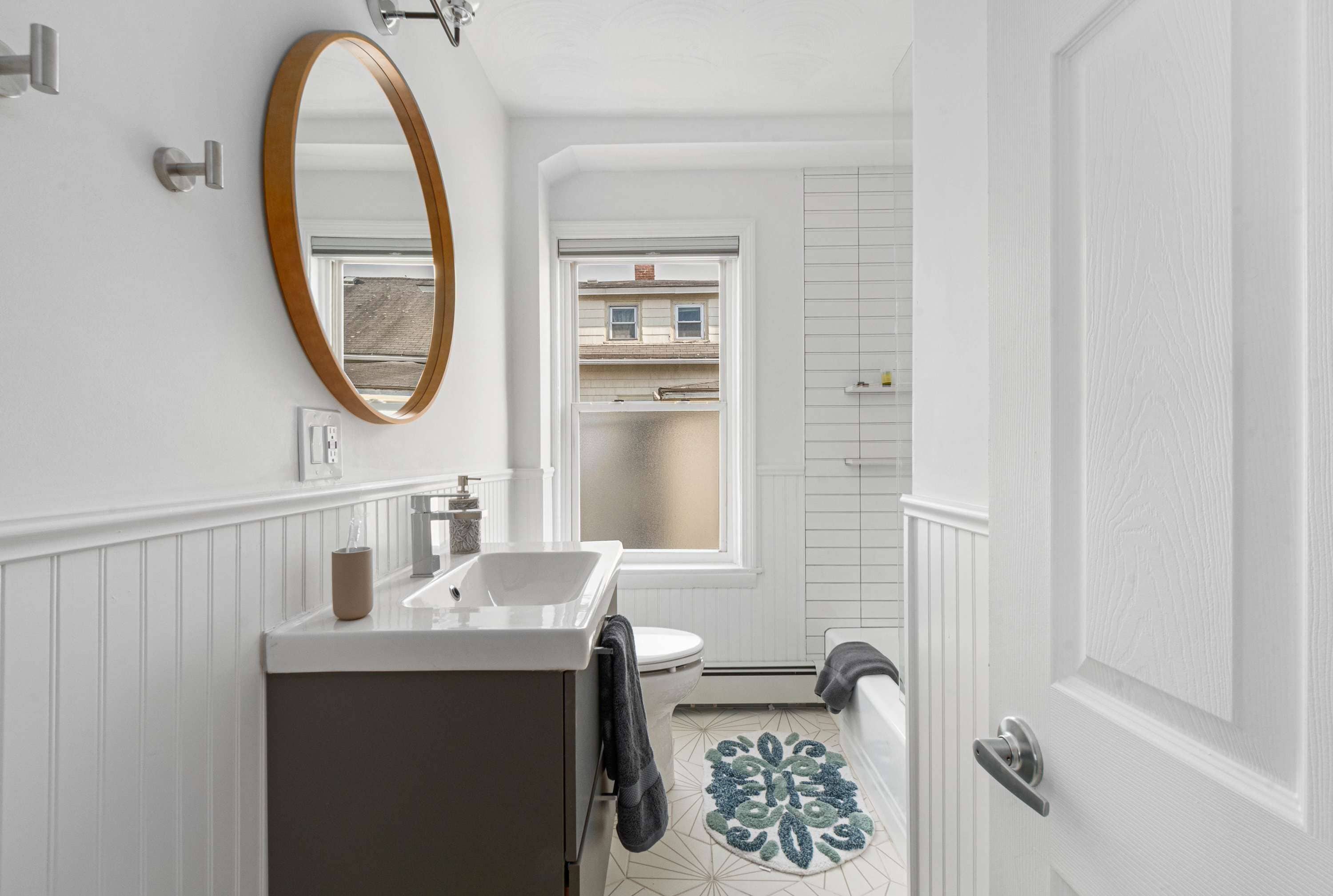 A bathroom with a white sink, a mirror, a toilet, and a shower.