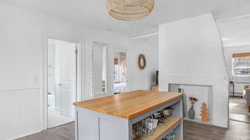 Une cuisine dotée d’un plan de travail en bois, de meubles blancs et d’un luminaire suspendu.