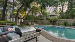 En baghave med swimmingpool, grill og et siddeområde med en sofa.