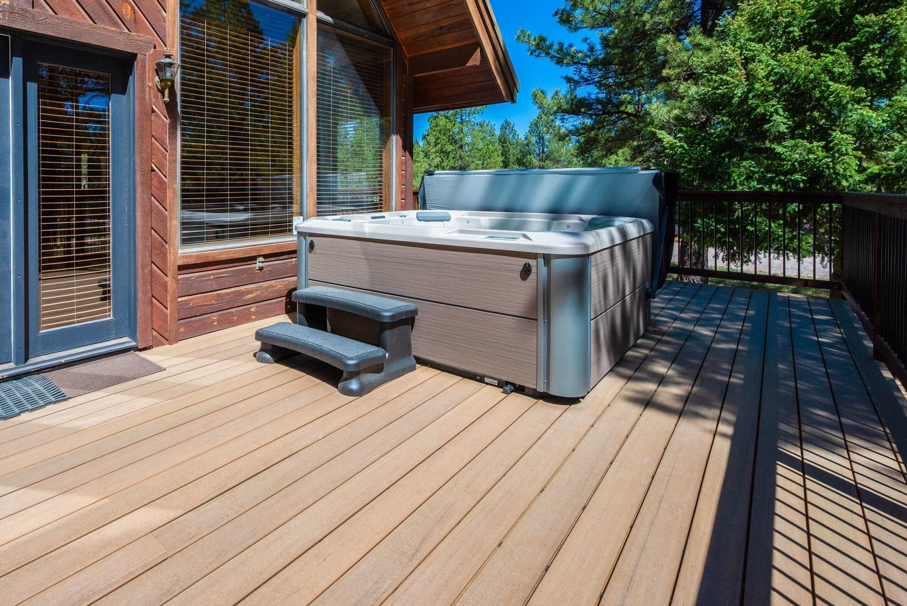 A wooden deck with a hot tub and a step-up seat.