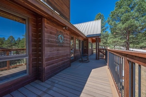 A wooden cabin with a covered porch and a metal railing.