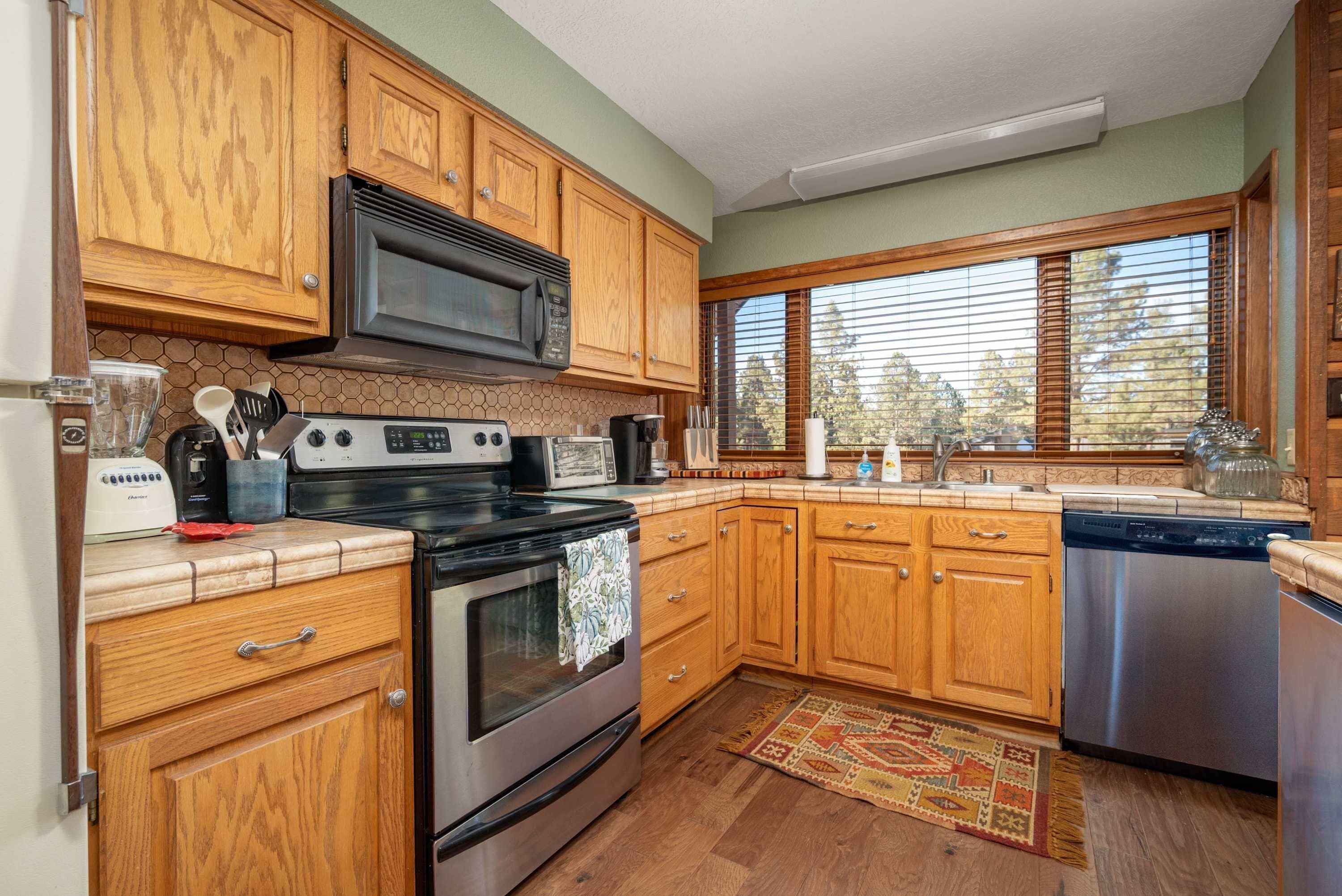 A modern kitchen with wooden cabinets, a stainless steel stove, a microwave, and a dishwasher.