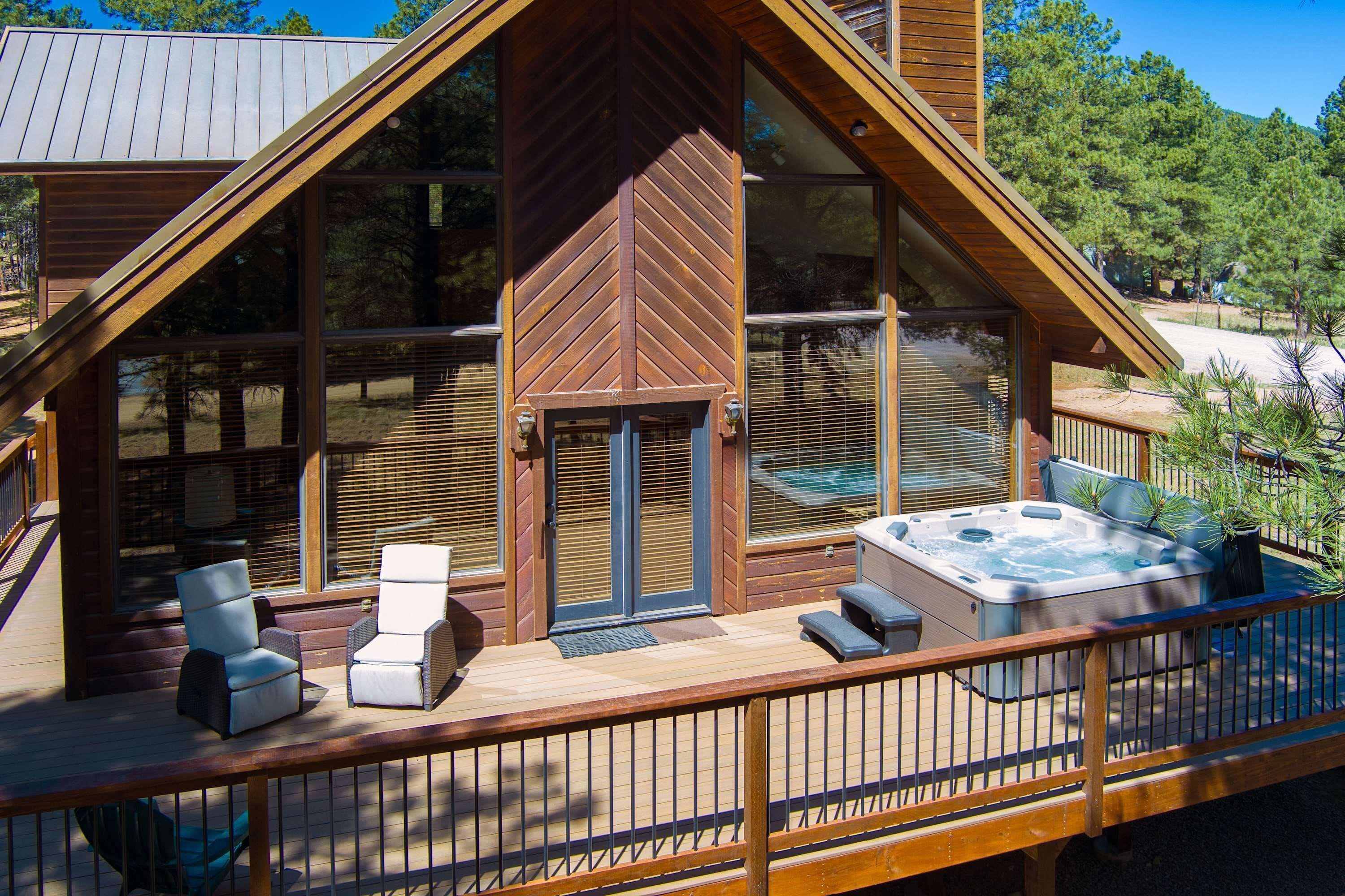 A wooden cabin with a deck, outdoor seating, and a hot tub.