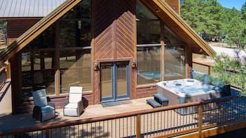 Una cabaña de madera con terraza, mobiliario exterior y un jacuzzi.