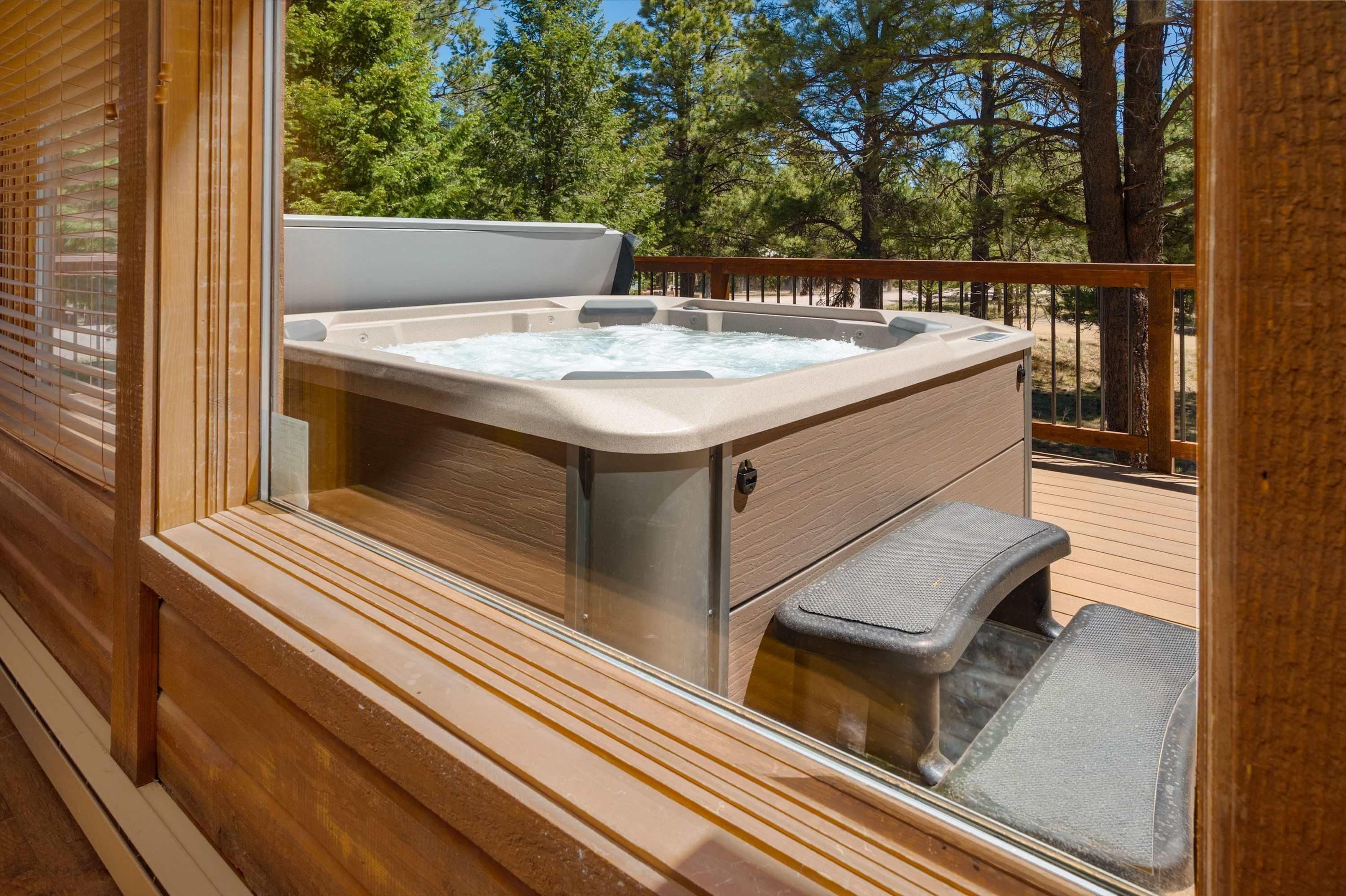 Ein Whirlpool auf einer Holzterrasse mit Blick auf Bäume.