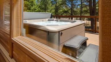 Ein Whirlpool auf einer Holzterrasse mit Blick auf Bäume.