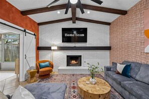 Un salon moderne avec une cheminée, un téléviseur fixé au mur et un canapé.
