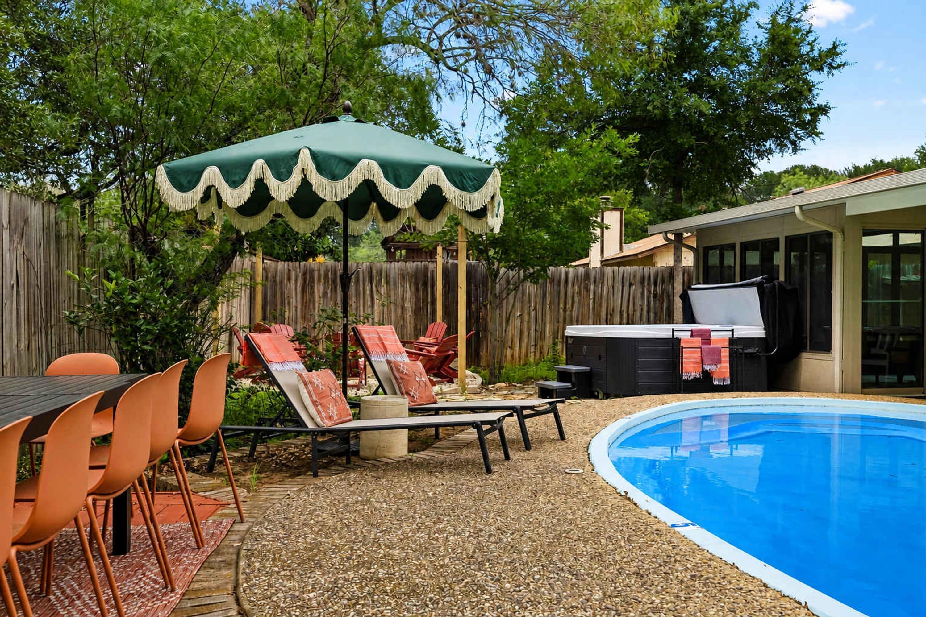 Un patio trasero con piscina, mobiliario exterior y una parrilla.