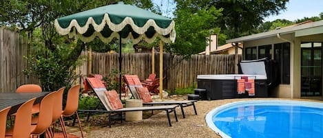 Un patio trasero con piscina, mobiliario exterior y una parrilla.