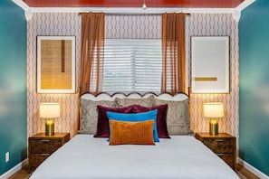 A bedroom with a bed, two bedside tables, a window with curtains, and two wall-mounted lamps. - Honky Tonk Dreams Pool - Hot Tub - Games (San Antonio)