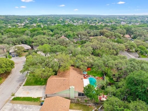 A residential area with houses surrounded by trees, a swimming pool, and a clear sky. - Honky Tonk Dreams Pool - Hot Tub - Games (San Antonio)
