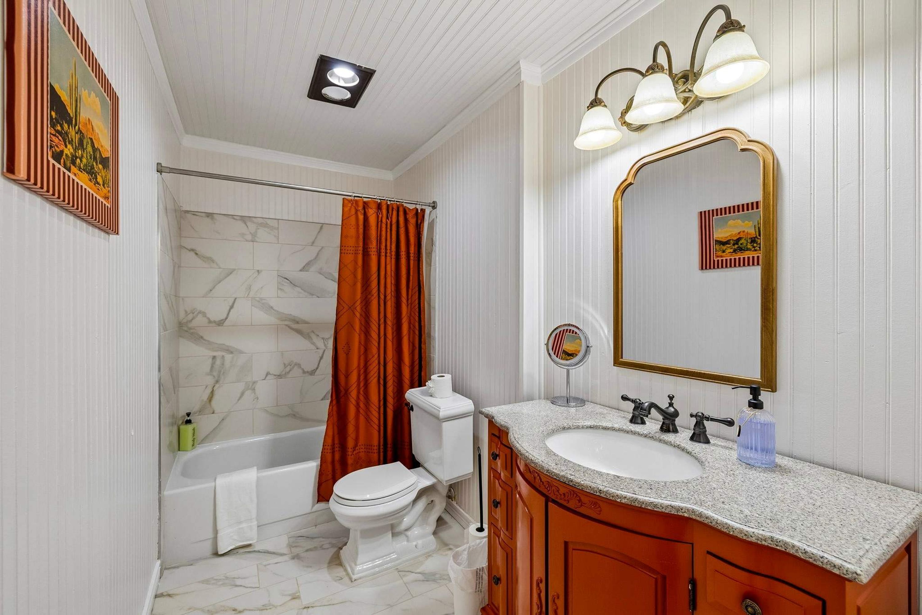 Une salle de bain comprenant une baignoire, des toilettes, un meuble-lavabo et un miroir.