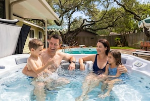A family of four in a hot tub with a backyard setting. - Honky Tonk Dreams Pool - Hot Tub - Games (San Antonio)