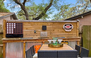 Un espace bar extérieur doté d’un comptoir en bois, d’une enseigne de la brasserie Kona Brewing Co. et de sièges extérieurs avec des chaises en osier.