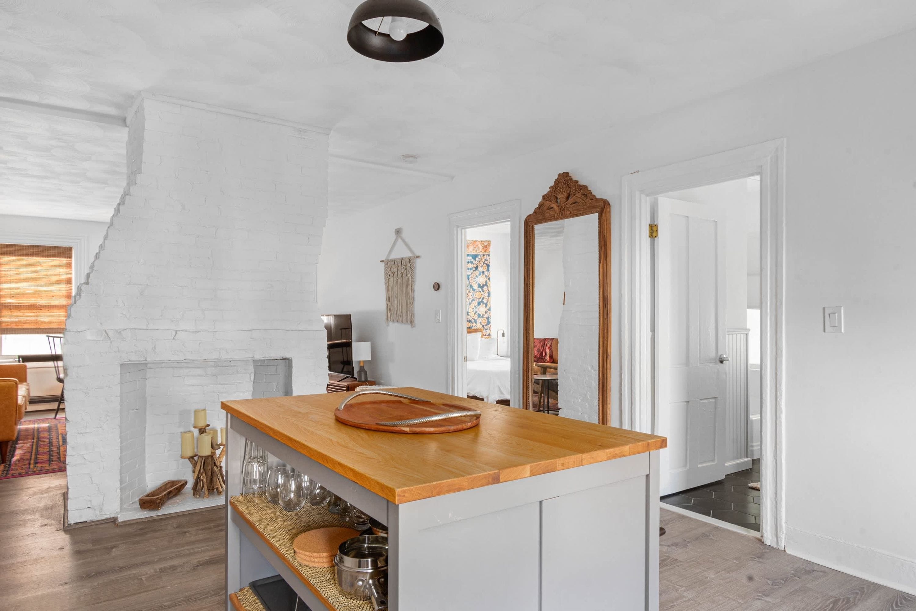 A kitchen with a wooden countertop, a hanging macrame wall decoration, and a large mirror.