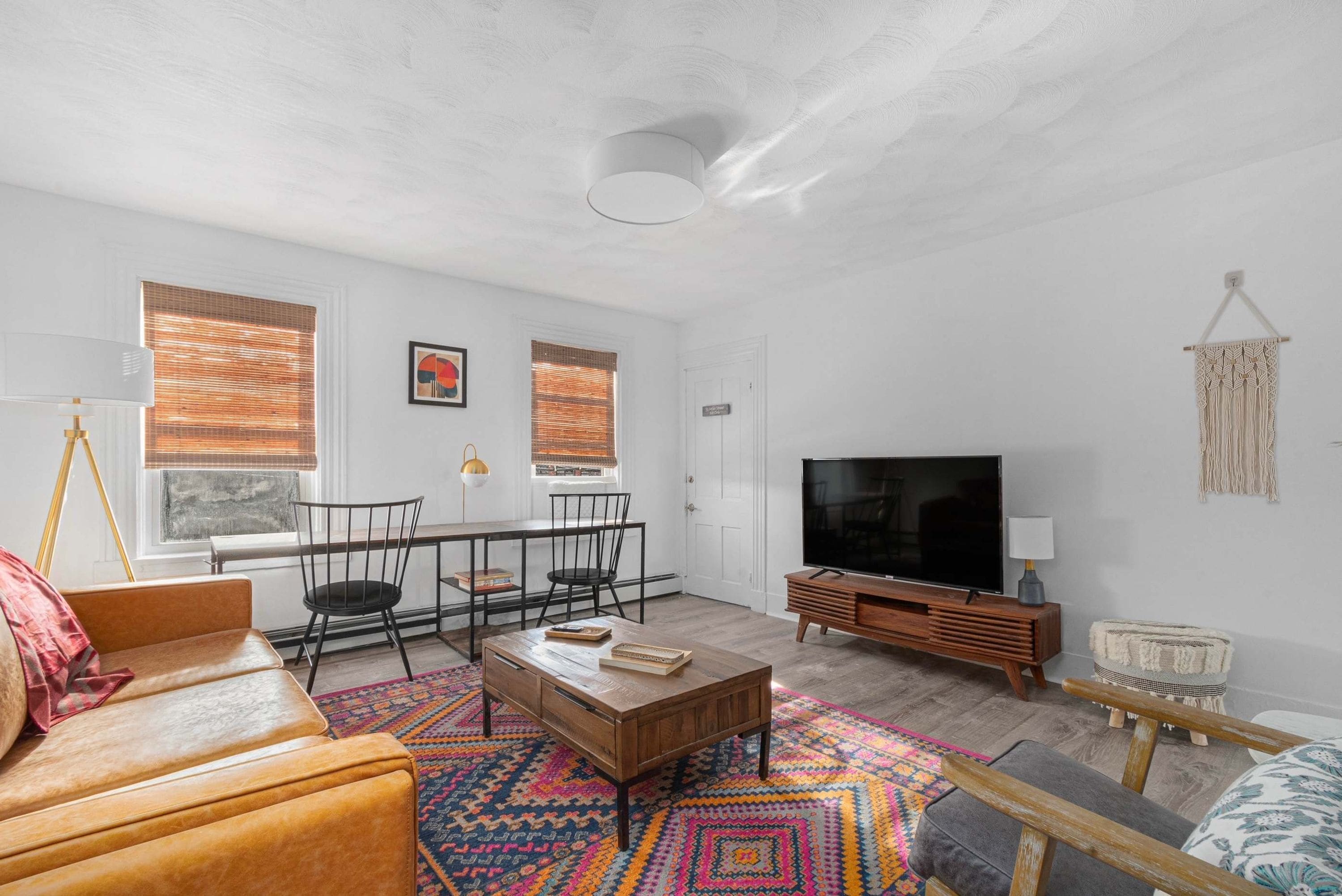 A modern living room with a sofa, coffee table, TV, and a patterned rug.