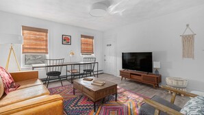Una sala de estar moderna con sofá, mesa de centro, televisor y alfombra estampada.