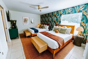A hotel room with a bed, two bedside tables, a bench, a ceiling fan, a green cabinet, and a wall with a leaf pattern. - Sleeps 10 Outdoor Oasis Heated Pool Grill (Bradenton)