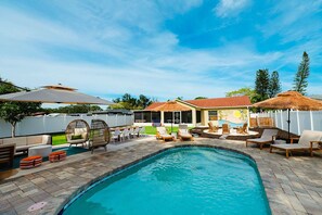Una piscina con sillones de descanso y zona de comedor.