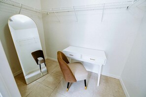 Et lille, hvidt rum med et skrivebord, en stol og et stort spejl.