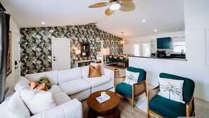 Ein modernes Wohnzimmer mit einem weißen Sofa, einem runden Couchtisch und einem Deckenventilator.