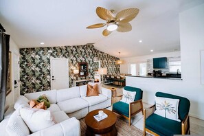 Ein modernes Wohnzimmer mit einem weißen Sofa, einem runden Couchtisch und einem Deckenventilator.
