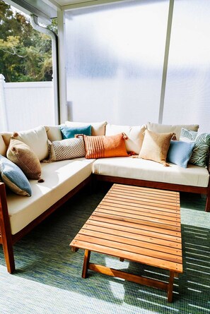 A sectional sofa with multiple cushions and a wooden coffee table in a sunlit room with a view. - Sleeps 10 Outdoor Oasis Heated Pool Grill (Bradenton)